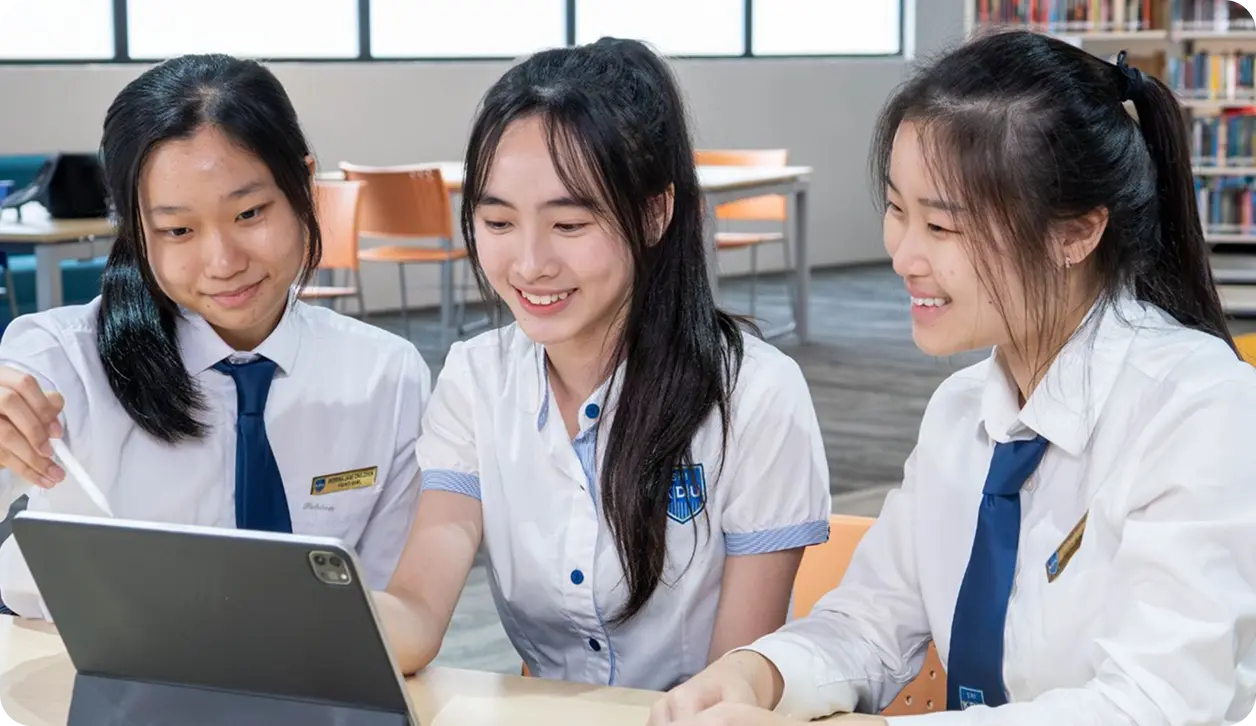 Students collaborating on a tablet in the library